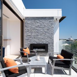This outdoor seating set perfectly compliments the grey tones of this homes outdoor fireplace and stone wall.